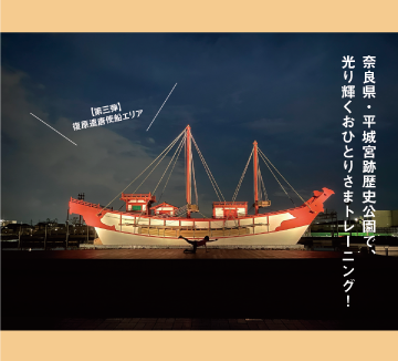 夜間にライトアップされた奈良県・平城宮跡歴史公園の船の模型をバックに体操する女性の写真です。